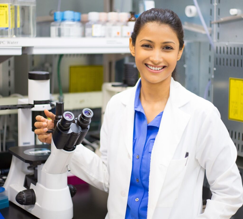 A woman scientist smiling while holding a microscope